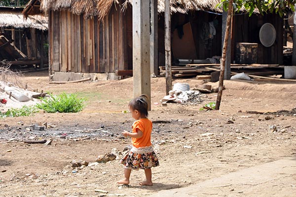 Criança brincando entre as casas de um povoado no Laos